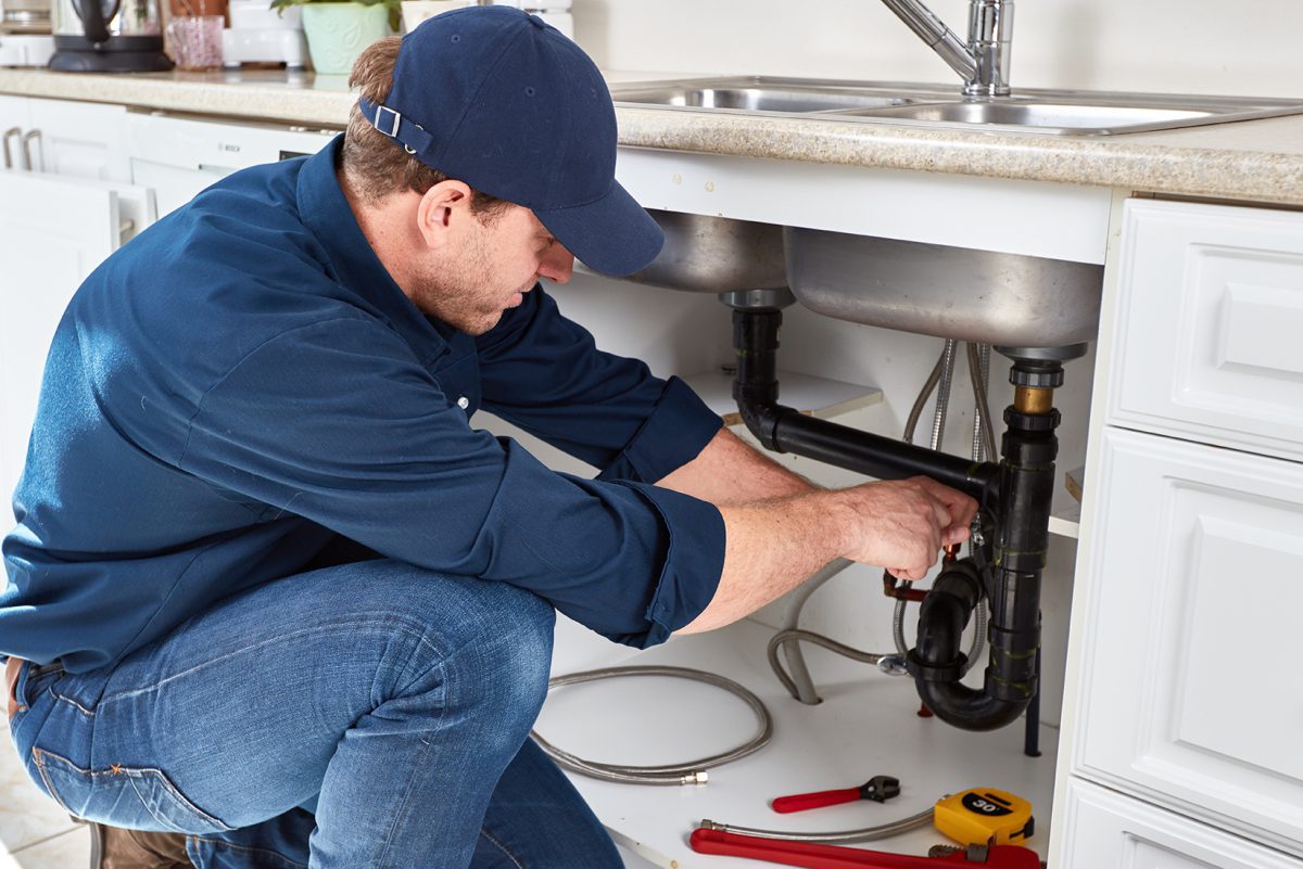 Plumber At Work Installing A Kitchen