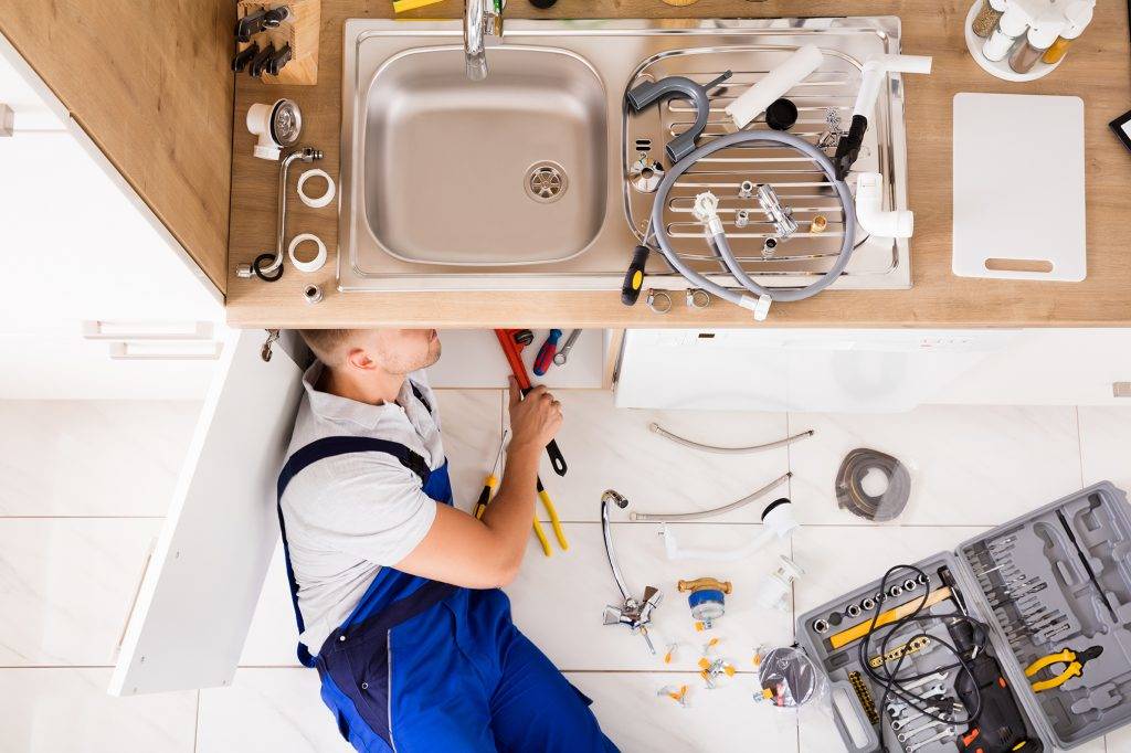 Plumber Working Under Sink